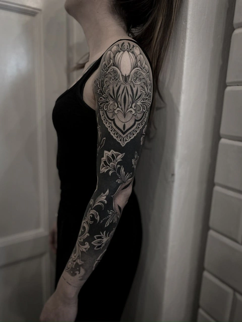 Czarno-biały, graficzny, ornamentowy tatuaż na rękawie w stylu blackwork, autorstwa Klaudii z Mongo Tattoo