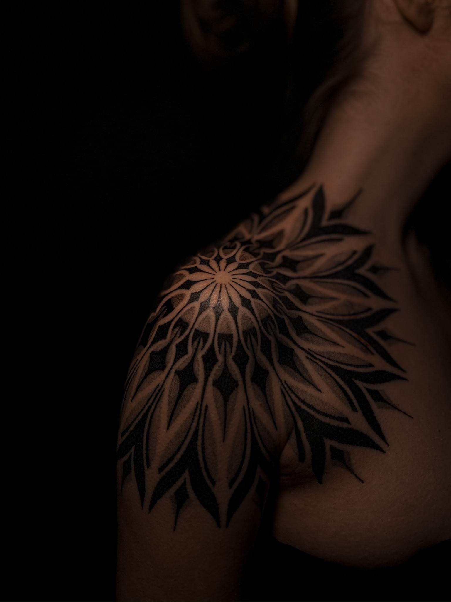 Czarny geometryczny tatuaż mandala na ramieniu